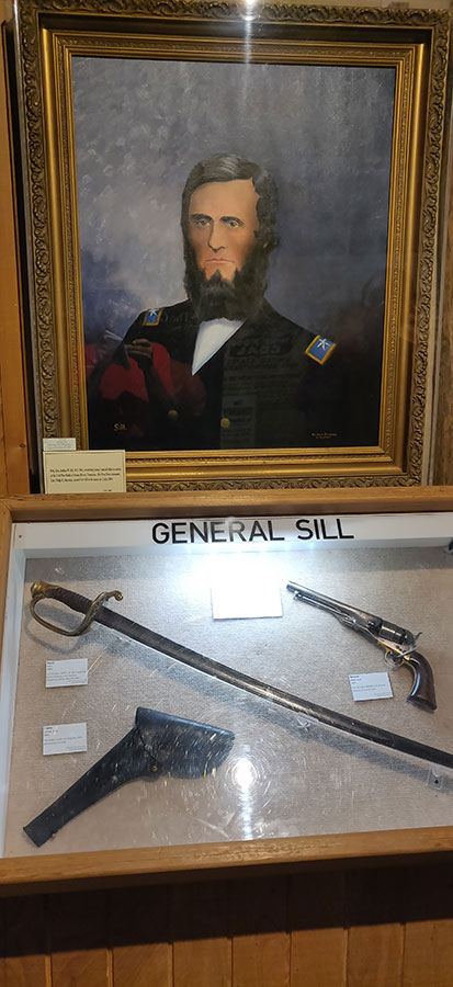 A portrait of General Sill along with some of his possessions, including a gun with holster and a sword.